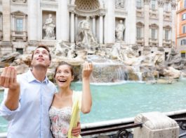 Una coppia di turisti stranieri lanciano la monetina nella fontana di Trevi a Roma