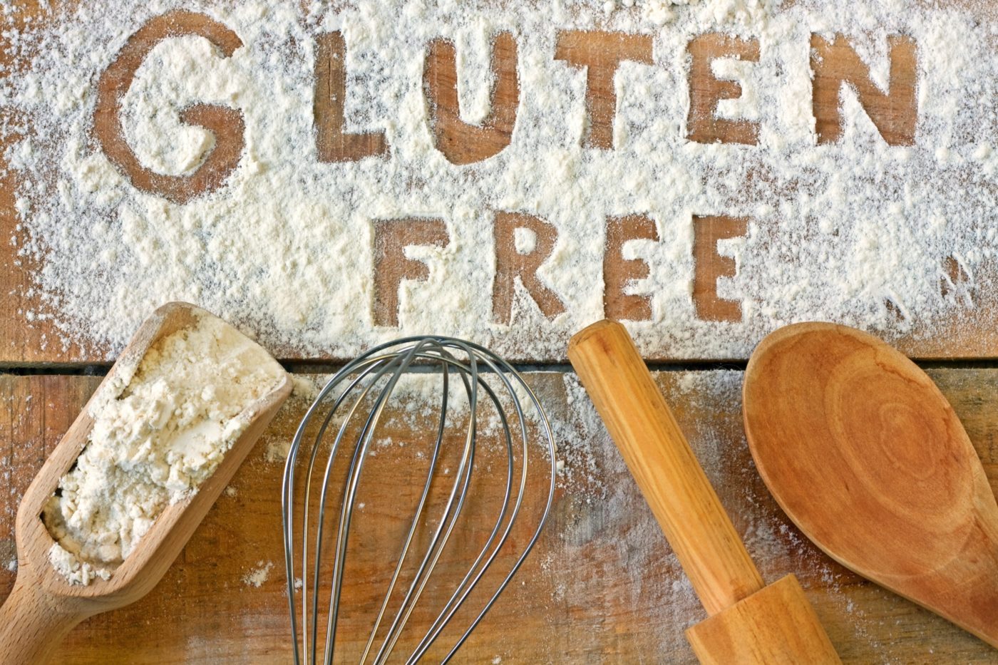 attrezzature da cucina su un piano di legno infarinato e la scritta gluten free