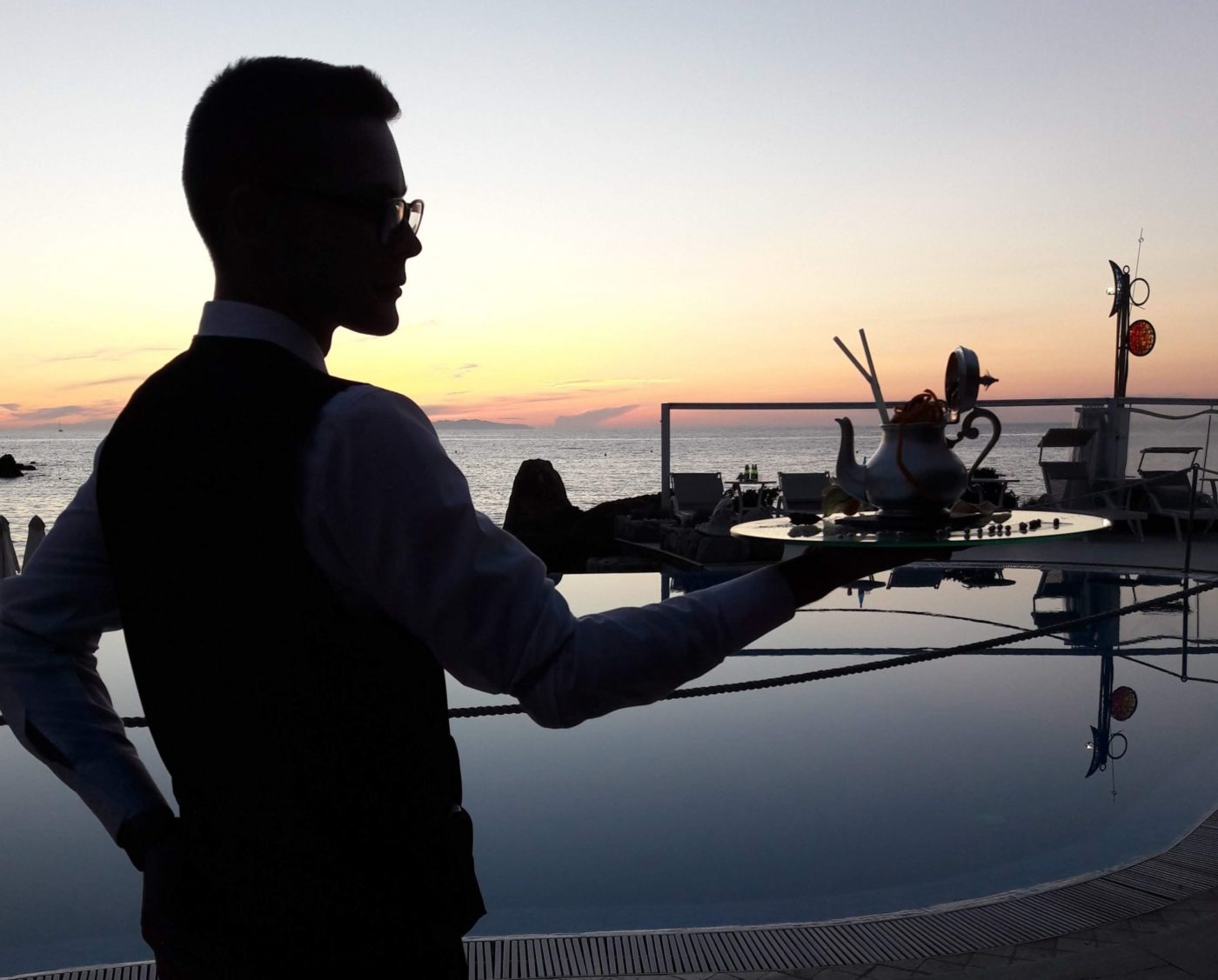 Un barman dell'Hermitage all'Elba con un vassoio mentre serve un cocktail in piscina