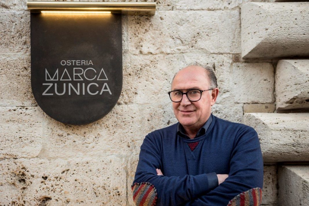 Daniele Zunica di fianco all'insegna del ristorante Osteria Marca Zunica